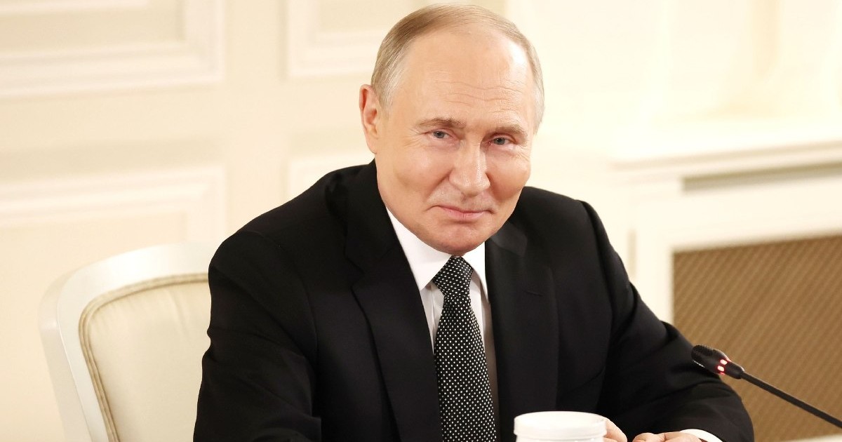 Președintele rus Vladimir Putin, îmbrăcat în costum negru, cămașă albă și cravată neagră, așezat pe un scaun bej, la o întâlnire cu presa, 18 iunie 2025
