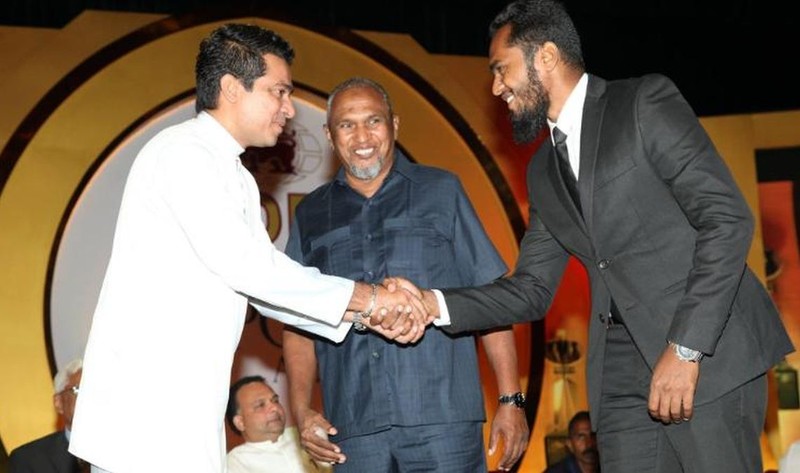 A photo posted in 2016 on the Sri Lankan Minister of Science Technology and Research???s official facebook page from a 2016 event shows Sujeewa Senasinghe (in white), former State Minister of International Trade, shaking the hand of Imsath Ahmed Ibrahim as his father, billionaire spice trader Mohamed Ibrahim looks on. A neighbor of the family confirmed the identities of the men to CNN.