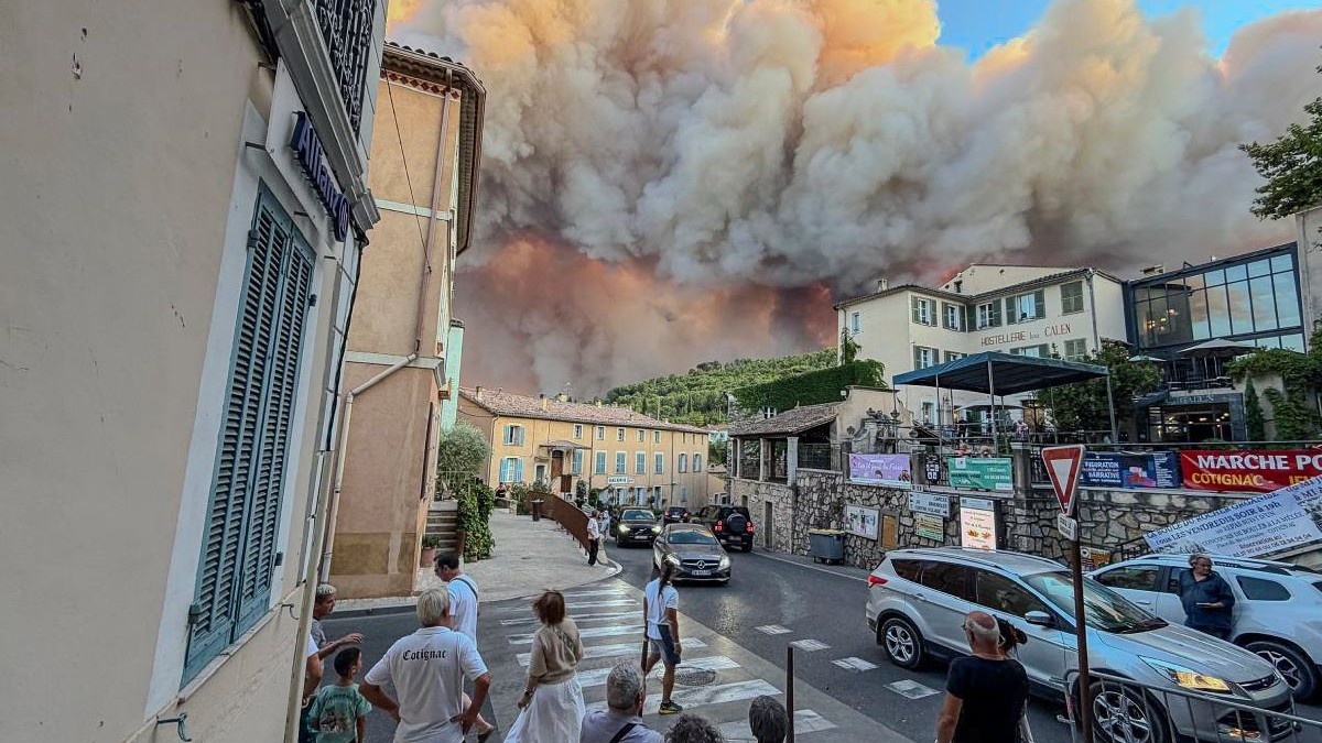 Trecătorii privesc fumul și flăcările unui incendiu de pădure pe 21 iulie 2026, în Cotignac, Franța. Peste 1.000 de pompieri au fost mobilizați pentru a stăpâni incendiul de pădure care se propagă rapid și care a distrus peste 2.500 de hectare în sudul Franței.