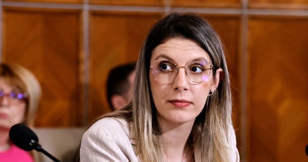 Imaginea o surprinde pe Diana Buzoianu în timpul unei ședințe, purtând ochelari și un sacou deschis la culoare, în timp ce privește atent spre interlocutori.