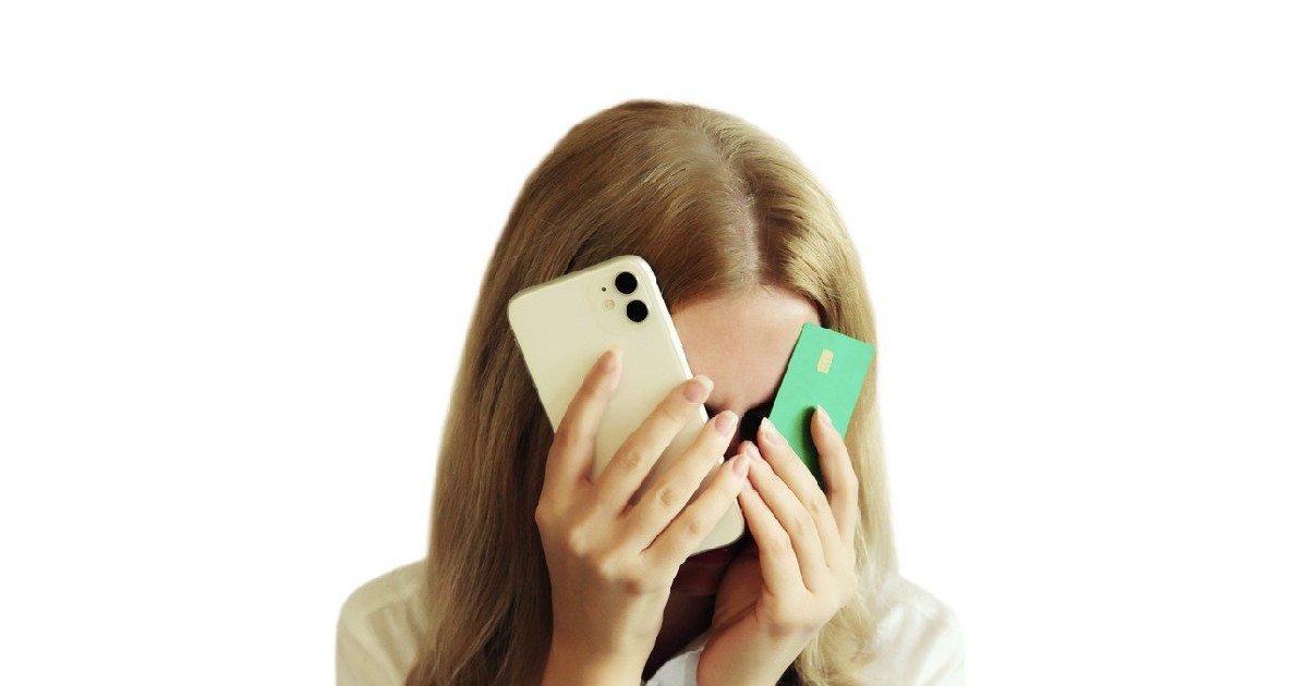 "Femeie tânără, vizibil afectată și disperată, ținând un telefon mobil și un card bancar în mână, își acoperă fața cu cealaltă mână