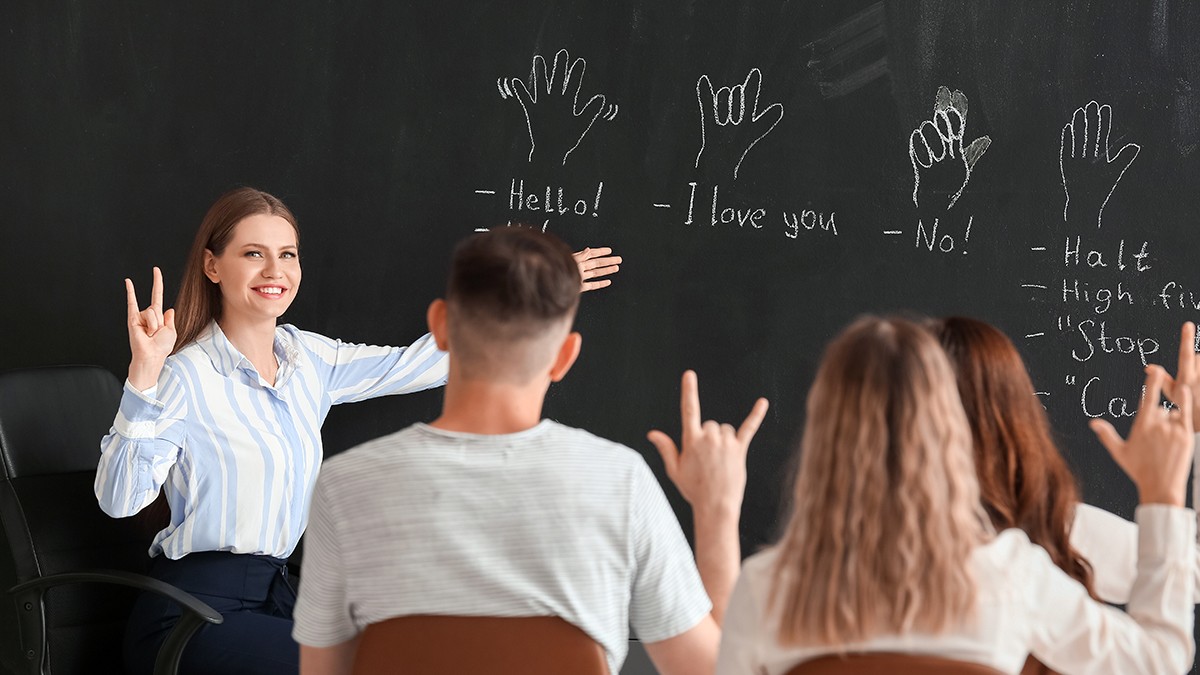 O profesoară îi învață pe studenți limbajul semnelor