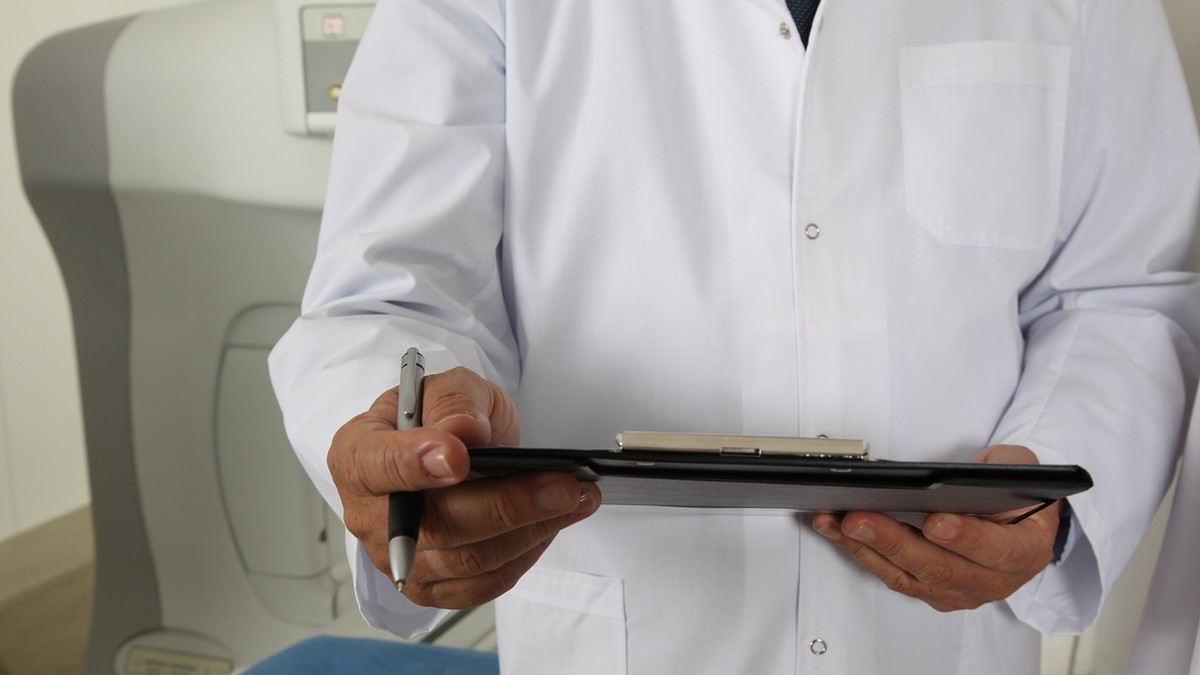 doctor cu documente în mână în fața unui aparat tomograf
