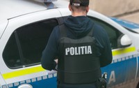 Un polițist cu vestă antiglonț, în timp ce încearcă să deschidă ușa unei mașini de Poliție