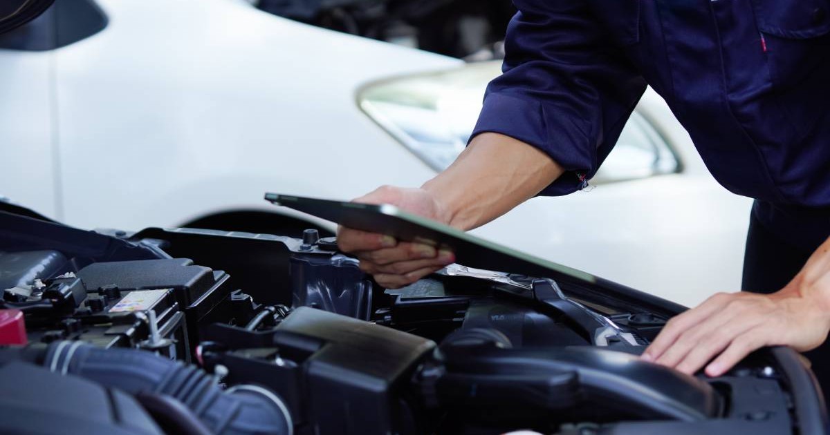 Mecanic în mănuși de lucru repară motorul mașinii în atelierul de reparații auto. Mecanic auto verifică vehiculul cu o cheie, remediază problemele. Service auto, întreținere, diagnosticare motor, reparații auto