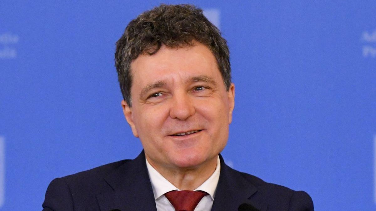 Președintele României, Nicușor Dan, în timpul unei conferințe de presă, poartă o cravată roșie și are un fundal albastru în spate