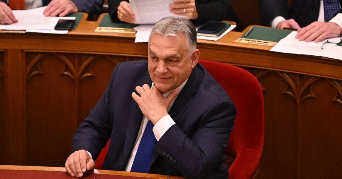 Premierul Viktor Orban, îmbrăcat la costum, cu o cravată albastră, în timp ce stă pe scaun în timpul unui discurs în Parlamentul Ungariei.