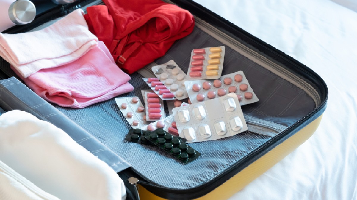 Geamantan galben în care se află mai multe tipuri de medicamente și multe haine