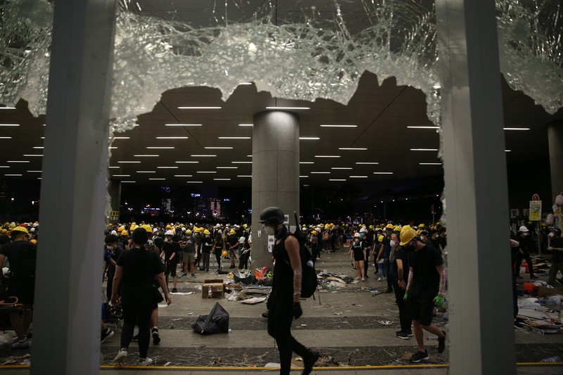 epa07687529 Protesters are seen through broken glass panels after they break into the Legislative Council building during the annual 01 July pro-democracy march in Hong Kong, China, 01 July 2019. Protesters are demanding the resignation of Hong Kong Chief Executive Carrie Lam and the full withdrawal of a suspended extradition bill. On 01 July, Hong Kong marks the 1997 transfer of sovereignty of Hong Kong from Britain to China. EPA-EFE/JEROME FAVRE
