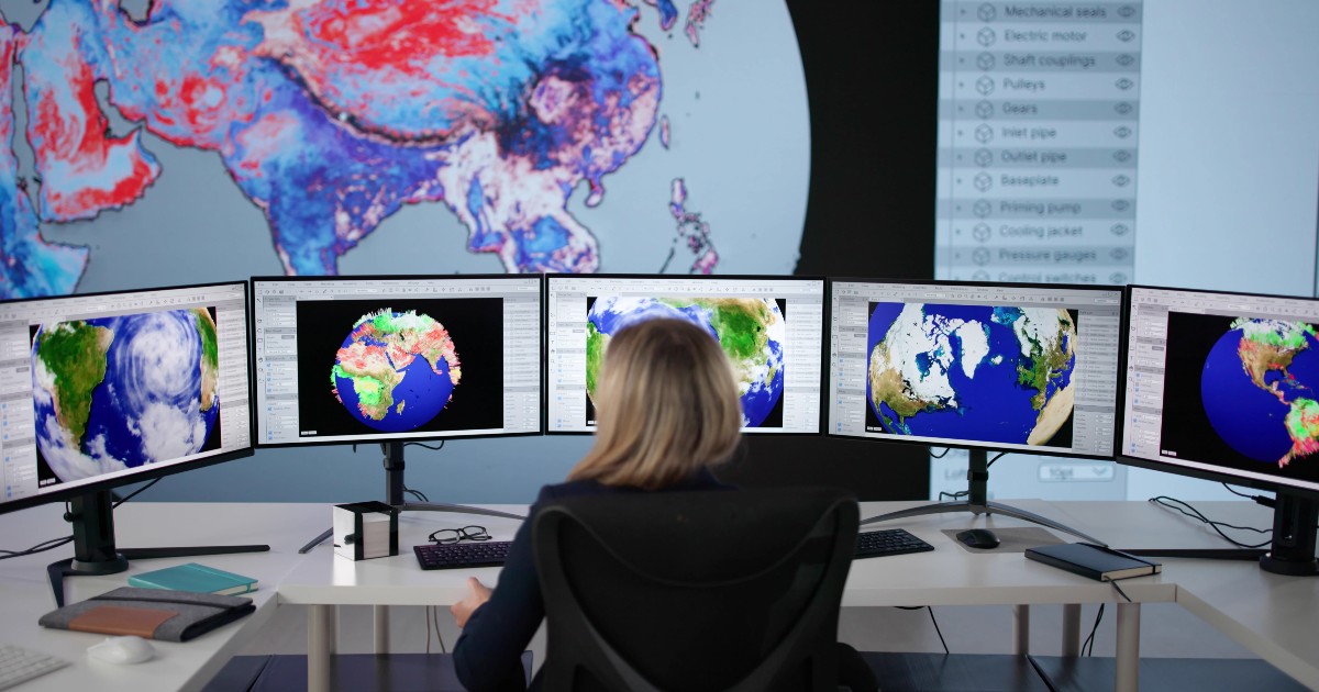 Imaginea prezintă o persoană văzută din spate care monitorizează hărți meteorologice și imagini ale globului pământesc afișate pe mai multe monitoare mari, într-un centru de comandă sau analiză a datelor.