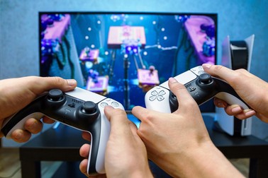 Doi tineri se joacă pe o consolă Sony PlayStation 5