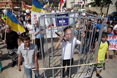 Un protestatar cu o mască a președintelui rus Vladimir Putin stă într-o închisoare simulată în timpul unei demonstrații sub deviza „Opriți teroarea lui Putin”, pe străzile centrale din Varșovia, Polonia, 27 iulie 2014. Mitingul, organizat de Euromaidanul din Varșovia și Open Dialog Foundation, a cerut sfârșitul ocupației ruse a Crimeei și independența Ucrainei | Foto: Profimedia
