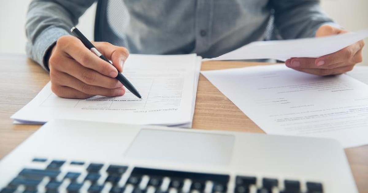 O persoană calculează în fața tastaturii cât are de plată
