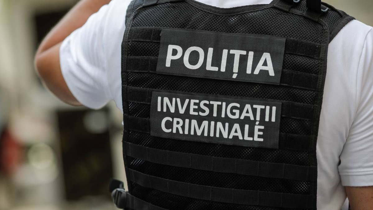 Detaliu politist român care poarta o vesta neagra cu inscriptia Politia. Investigatii Criminale