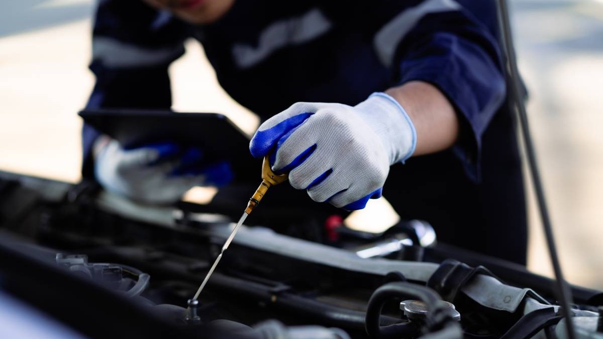 mecanic auto care verifica nivelul de ulei al motorului masinii cu ajutorul unei joje