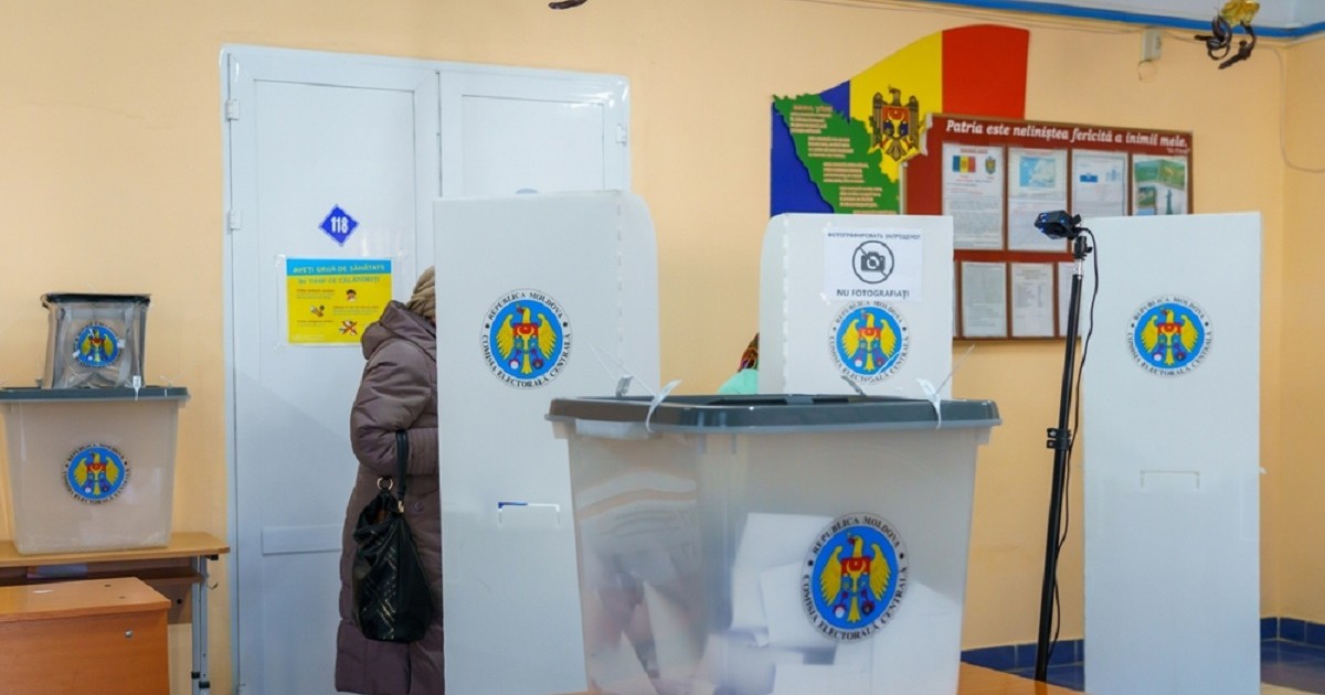 O femeie voteazî într-o secție de votare din Republica Moldova, unde sunt mai multe cabine de vot și urne pentru voturi