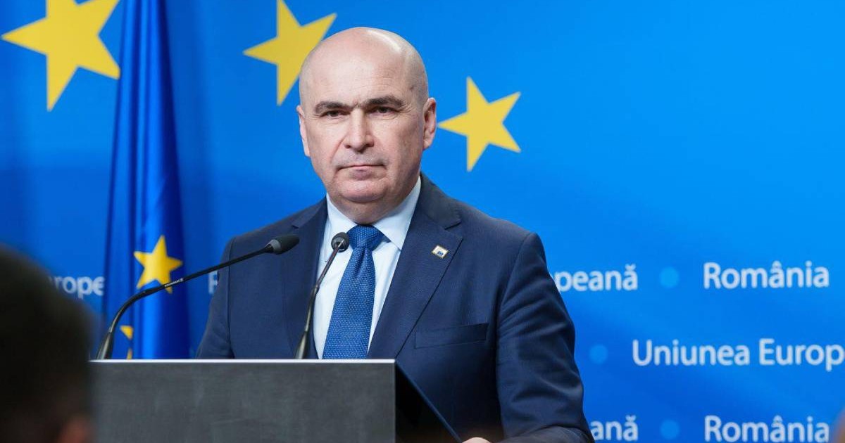 Ilie Bolojan în timpul unei conferințe de presă în Parlamentul European, poartă un costum și o cravată albastră.