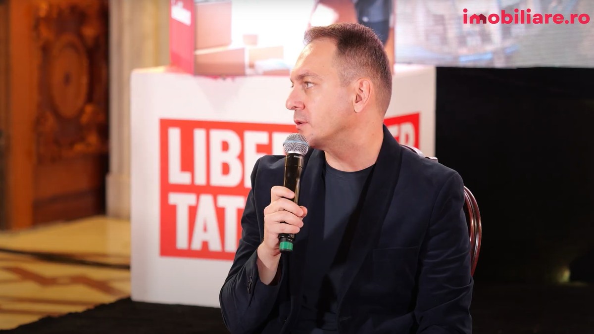 Bogdan Bălașa, General Manager HILS Development, la costum si maleta, vorbeste la microfon