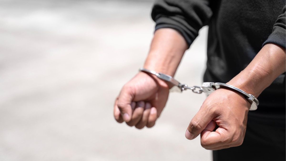 bărbat îmbrăcat într-o cămașă neagră, cu cătușe metalice pe mâini