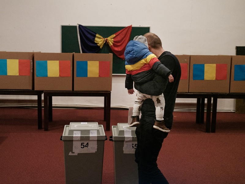 Un tată votează cu fiul său în brațe