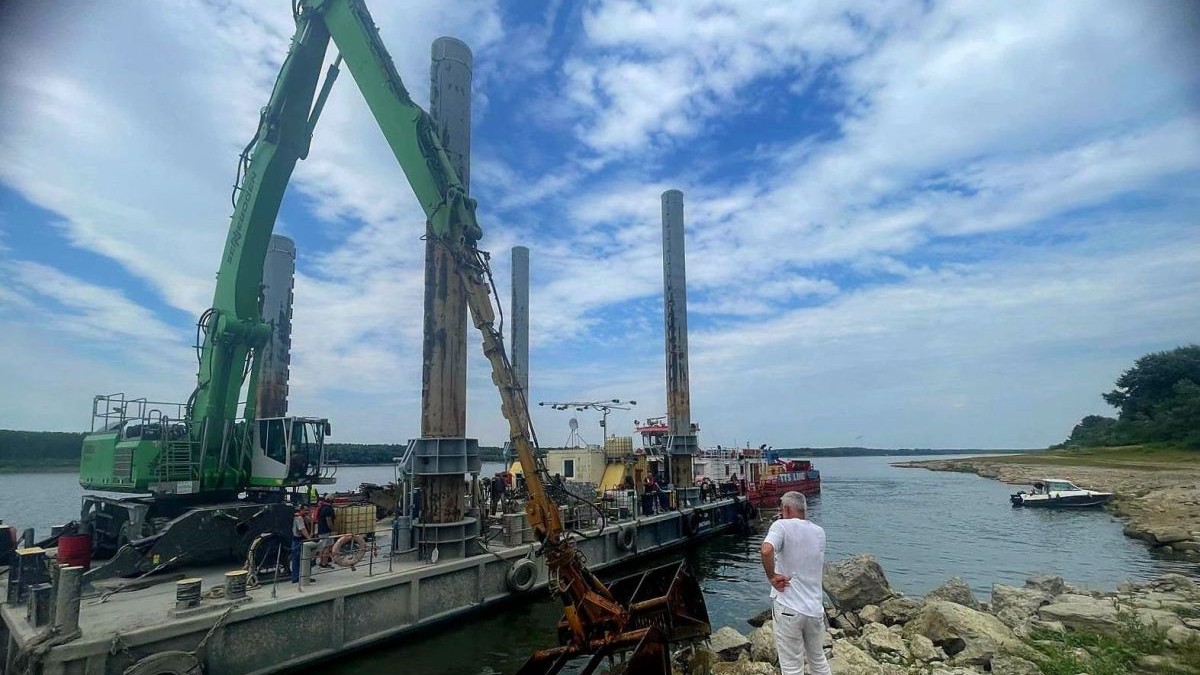 Un bărbat urmărește cum două excavatoare de 35 si 60 tone echipate cu picon sparg roca pentru a umple4 barje care, ulterior, vor fi scufundate în Dunăre. 3 august 2026