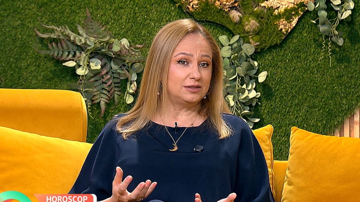Astrologul Cristina Demetrescu, îmbrăcată cu o bluză bleumarin, gesticulează din mâini și stă pe o canapea portocalie în studioul unei emisiuni Tv, București, 20 octombrie 2025