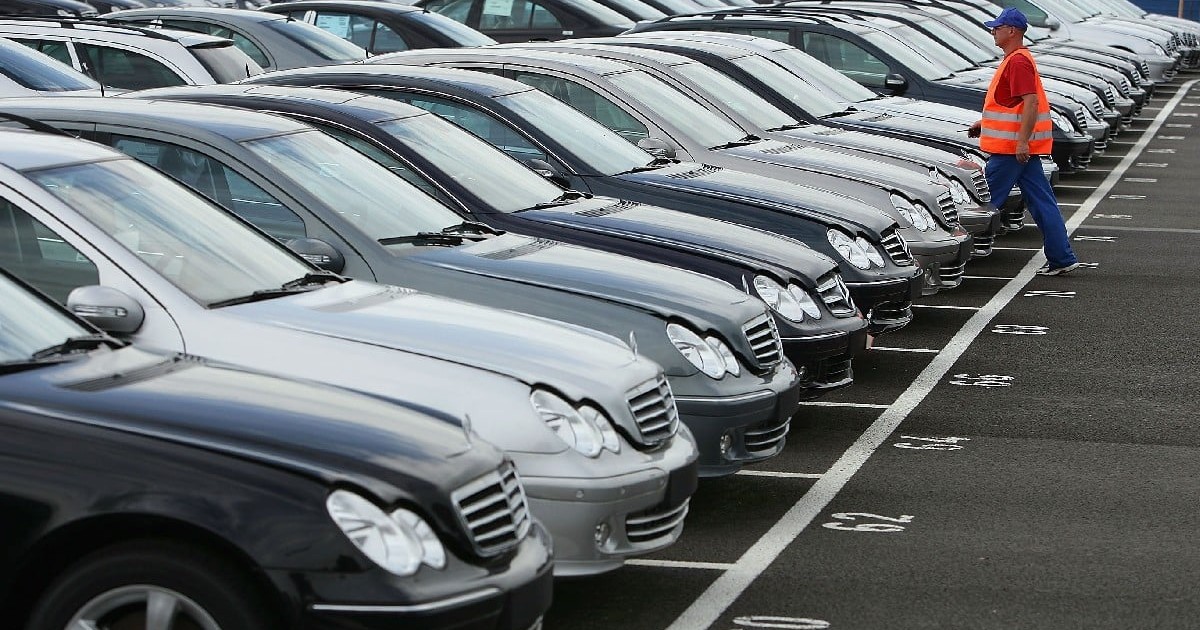 Parc auto de mașini de vanzare Mercedes vechi cu un om in vesta reflectorizantă