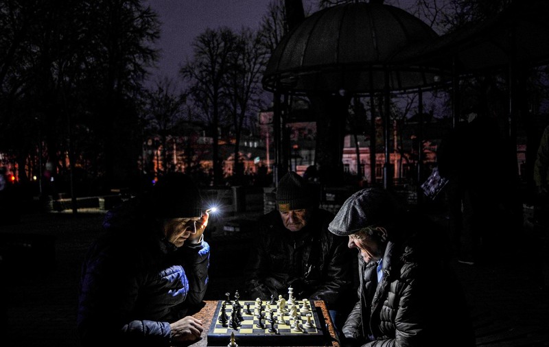 Imagini din Ucraina în beznă. Locuitorii încearcă să-și adapteze viața la noua realitate: șah la lumina lanternei, masa cu lumânări și cumpărături pe întuneric