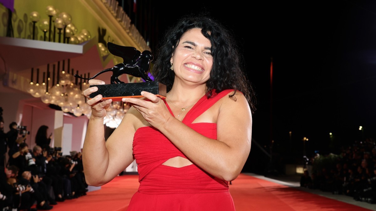 Regizoarea Alina Șerban, la Festivalul de Film de la Veneția, stă pe covorul roșu și ține în mână premiul