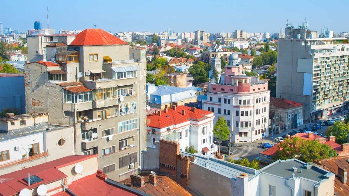 Imagine de sus din orașul București, se vad case si blocuri, în orizont cerul, într-o zi insorită