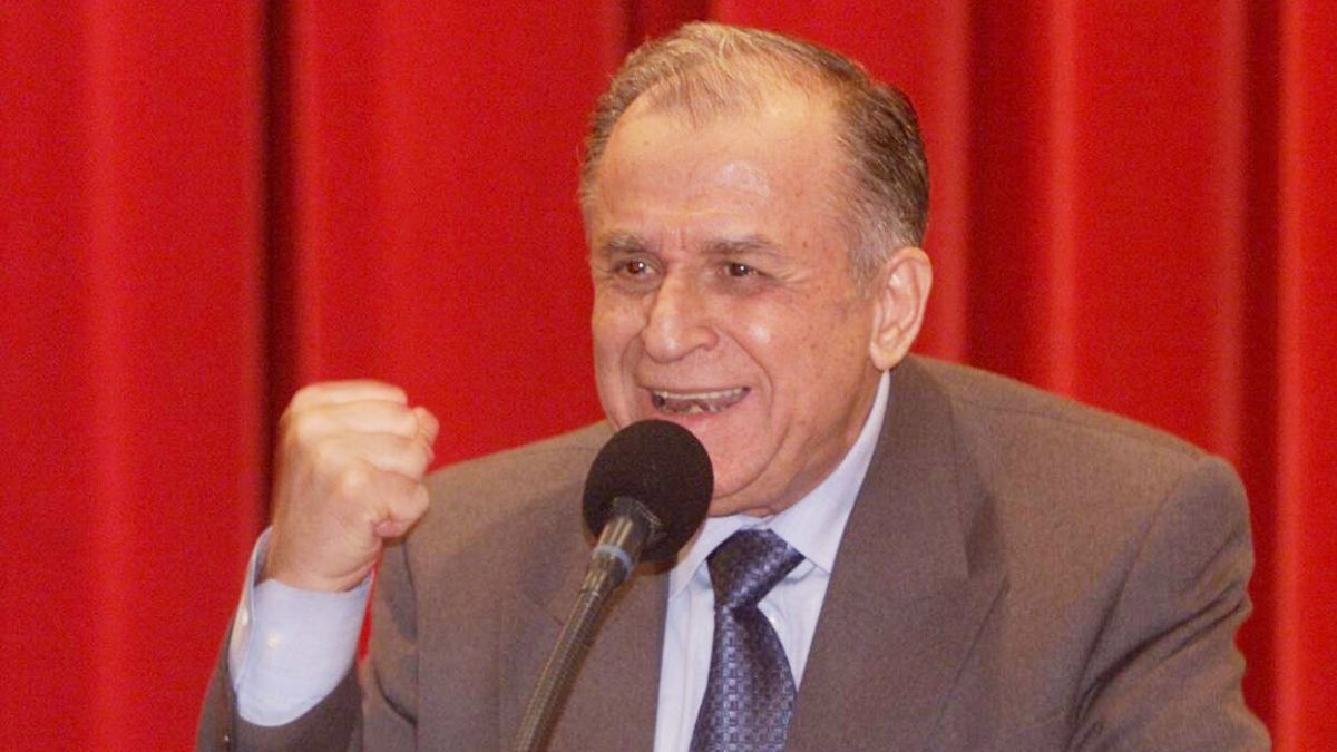 Ion Iliescu vorbește de la pupitru în timpul unei conferințe de presă ținând strâns pumnul drept și având pe fundal o draperie de culoare roșie, decembrie 2000