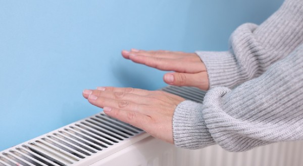 Femeie încălzindu-și mâna lângă radiator interior, closeup