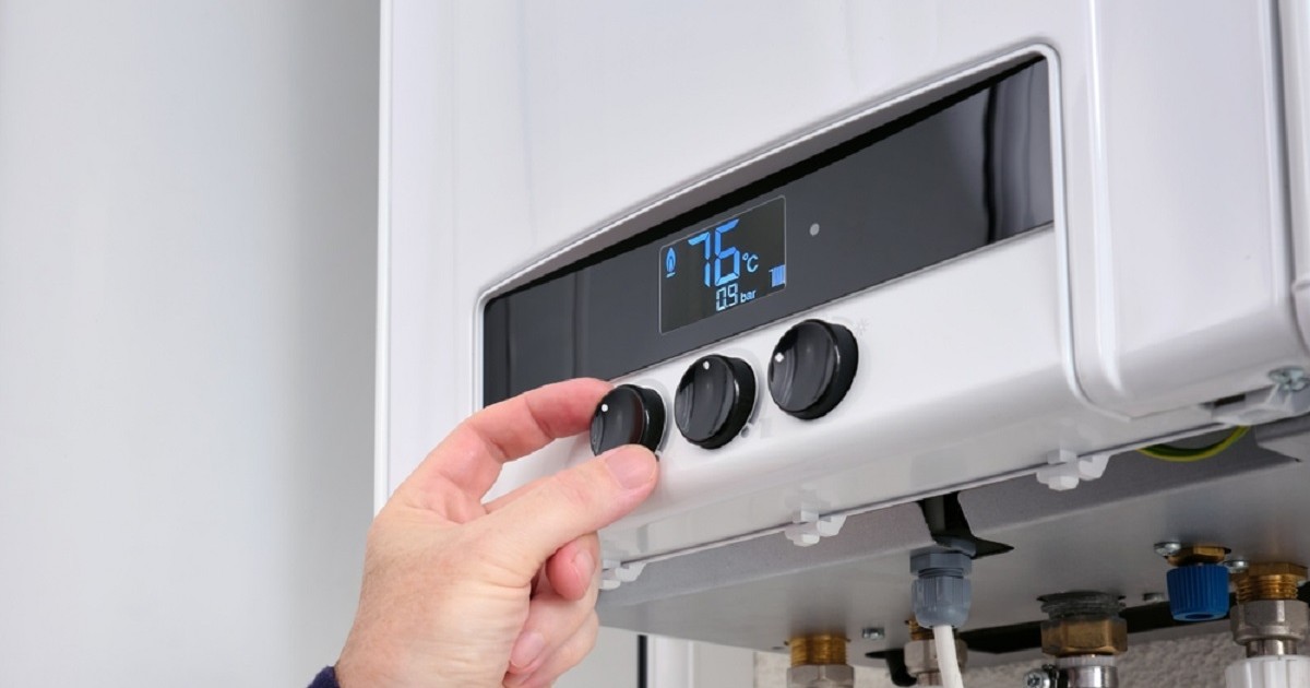 Cum să pregăteşti centrala termică pentru sezonul rece - Prim-plan al mâinii unui bărbat care se schimbă temperatura la centrala termică