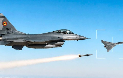 Imaginea ilustrează un avion de vânătoare F-16 al Forțelor Aeriene Române lansând o rachetă asupra unei drone militare încadrate în vizor pe cerul senin.