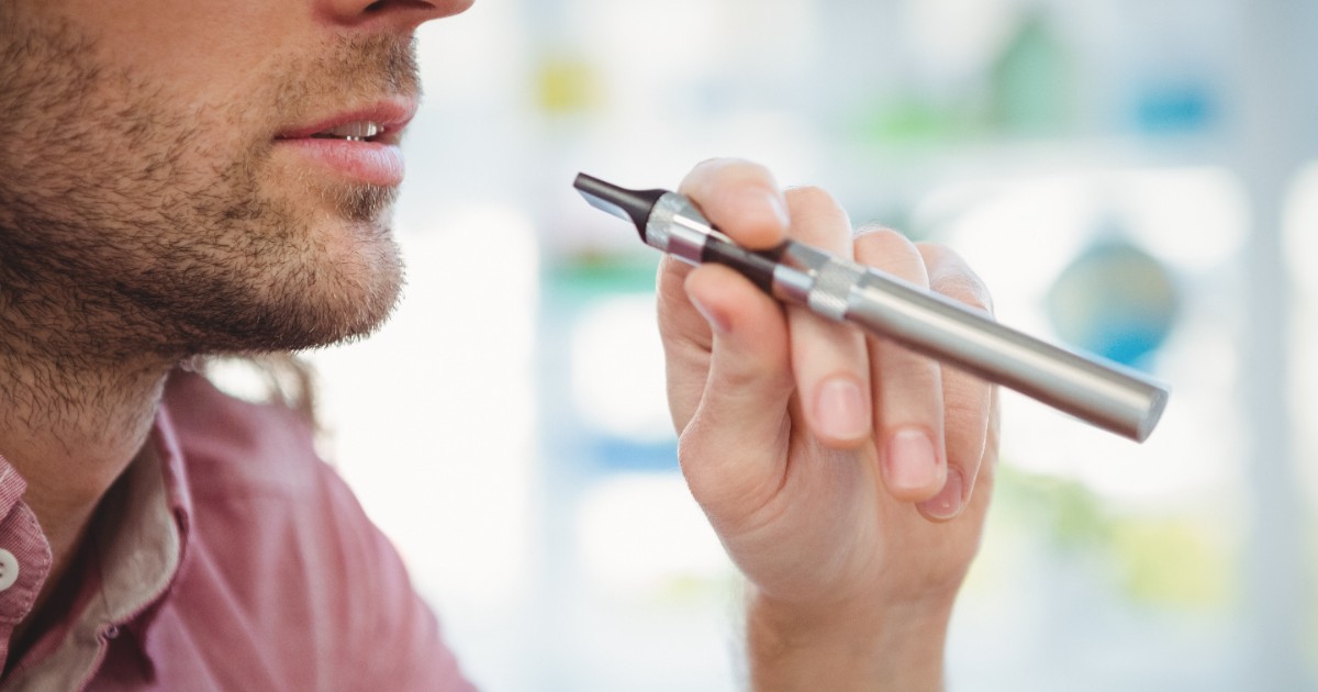 Un bărbat care ține în mână o țigară electronică