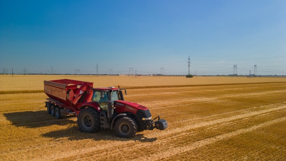 Un tractor roșu care a arat un lan de grâu și a strâns pe un câmp din România