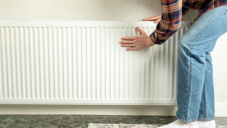 Persoana inspectează radiatorul pentru a se asigura că căldura este gata pentru sezonul de încălzire