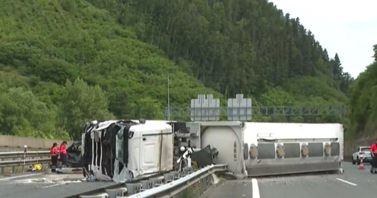 În imagine se vede un camion răsturnat pe o autostradă, după un accident grav care a blocat mai multe benzi de circulație. La fața locului intervin echipaje de urgență, în timp ce vehiculul avariat și resturile împrăștiate pe carosabil indică violența impactului.
