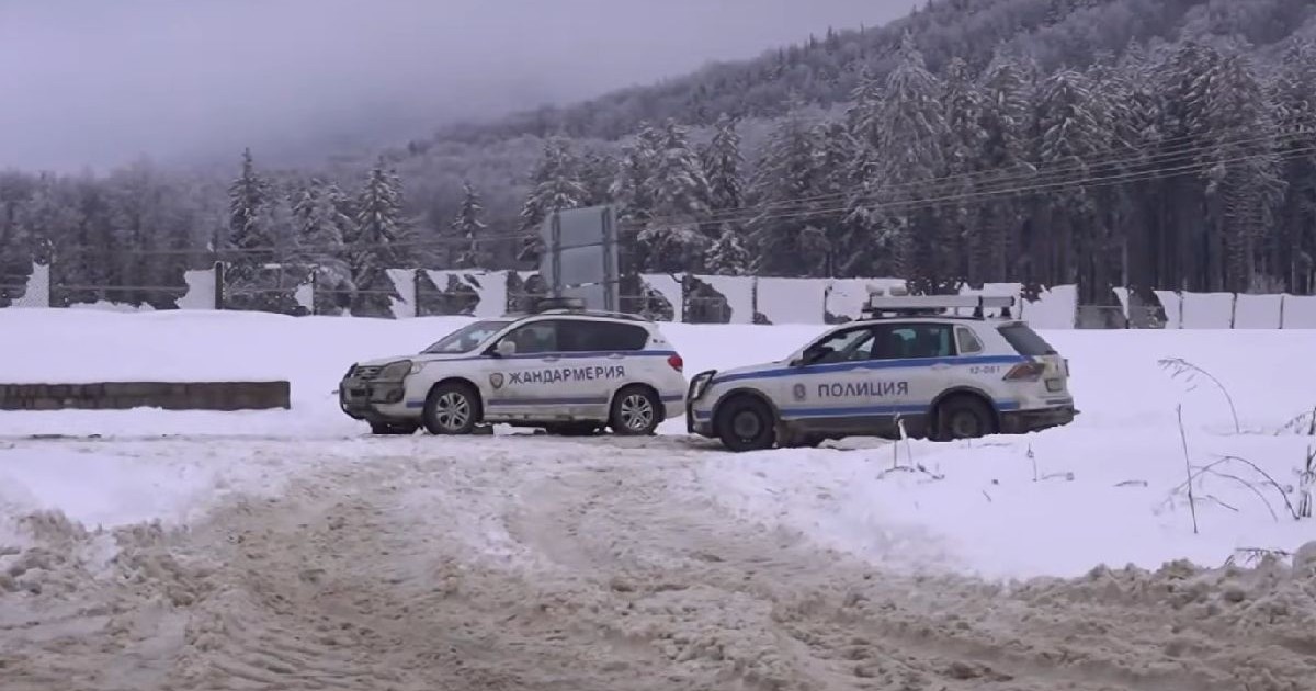 Fotografia surprinde două mașini de poliție bulgărești pe un drum acoperit de zăpadă într-o zonă împădurită.