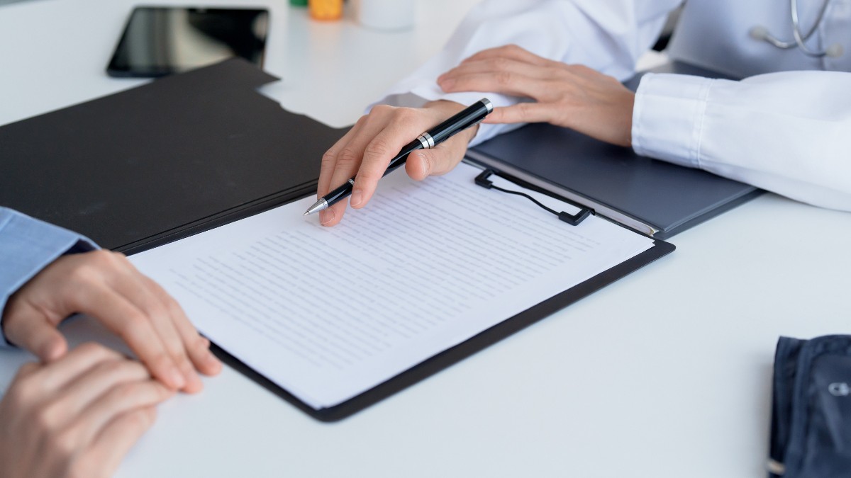 Un doctor în timp ce îi dă unui pacient un document de semnat