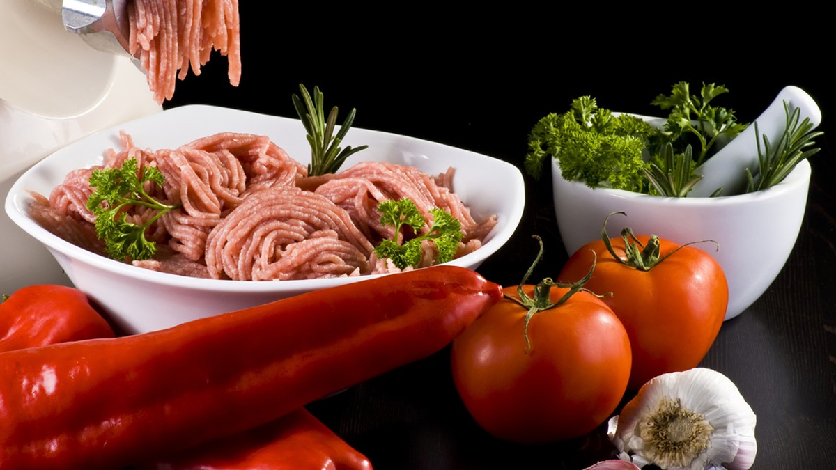 Reţetă de ardei umpluţi şi chifteluţe în sos de roşii - Imagine cu un bol cu carne tocată, alături de ardei şi roşii.