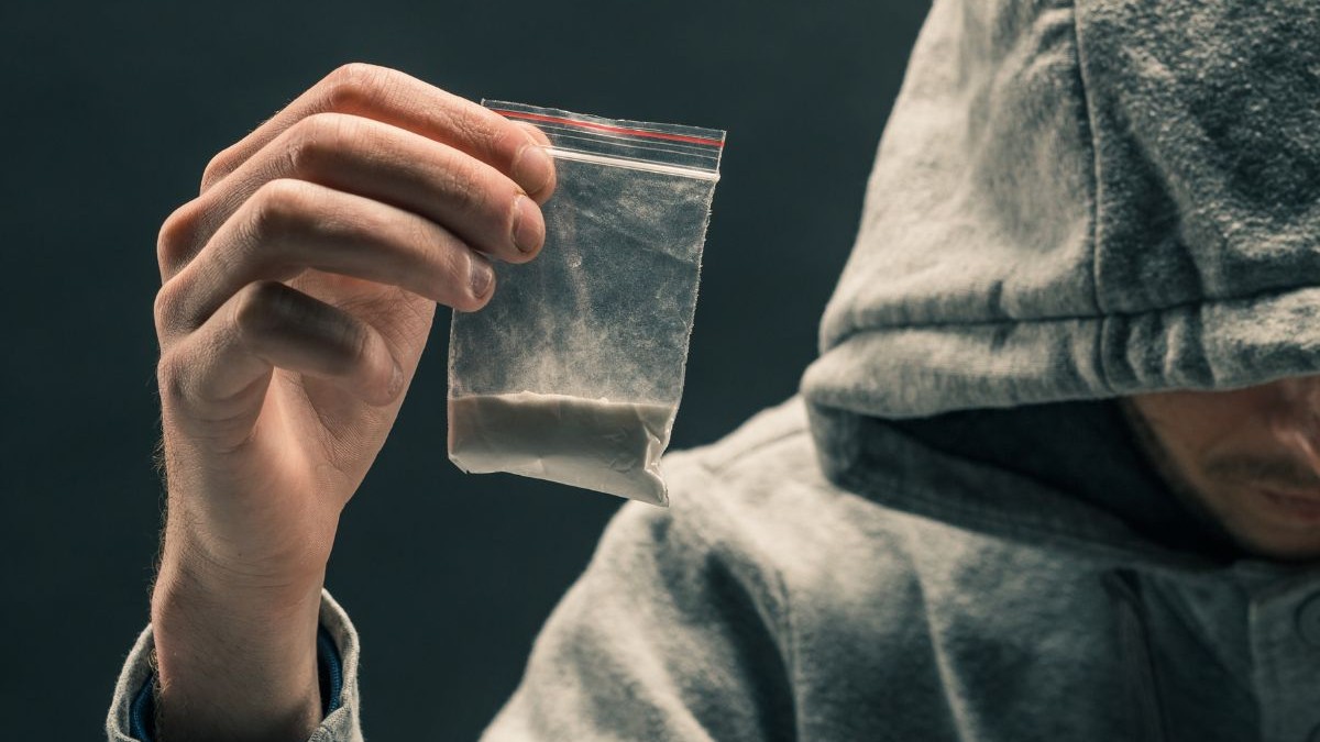 Bărbat care ține în mână o pungă transparentă de plastic cu o pudră albă