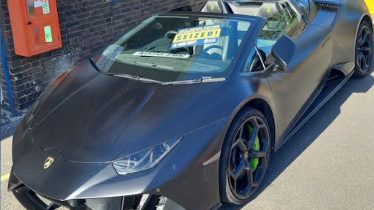 Lamborghini Huracán negru mat, care are lipit pe parbriz un afiș galben cu inscripția „SEIZED!”.