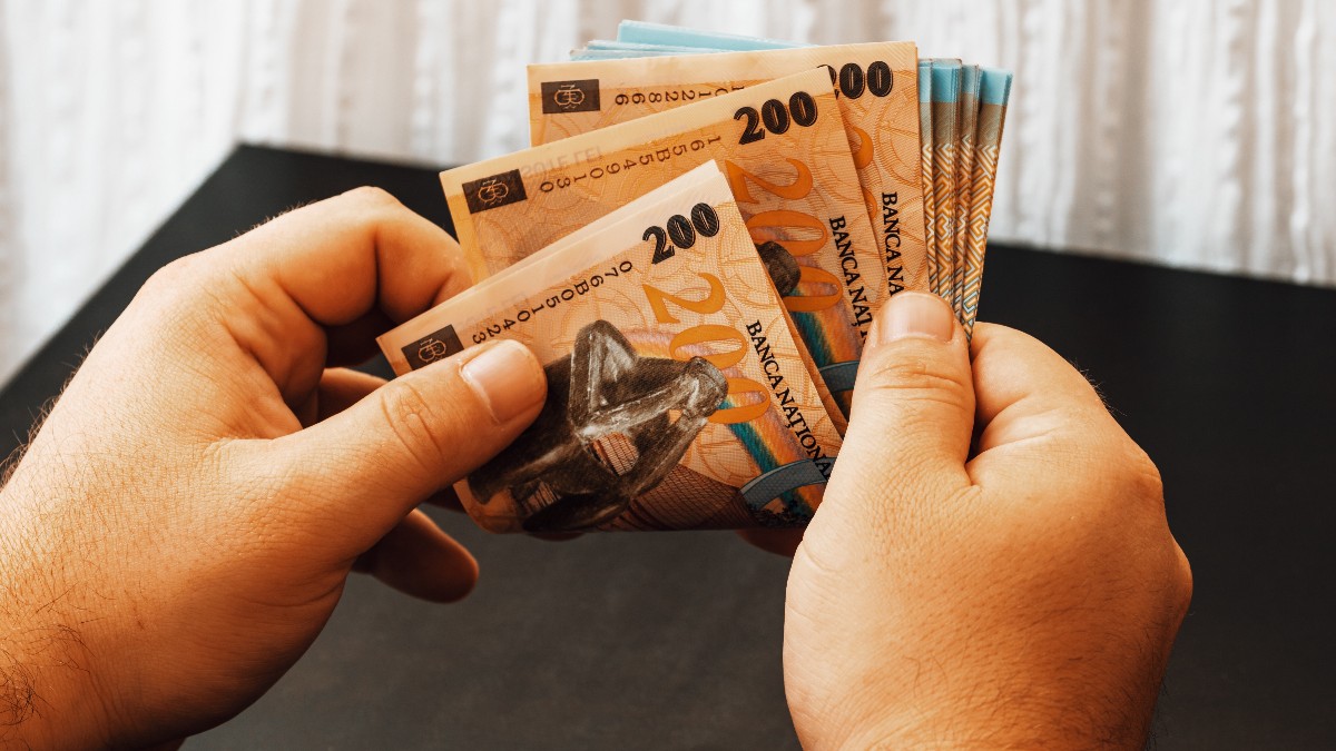 O femeie care numără bani, are hârtii de 200 de lei, pe care le ține în ambele palme