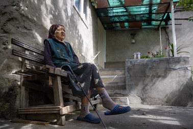 Maria Stemate, 93 de ani, privește spre șosea de pe „canapeaua” din curte. Sursa foto: Eli Driu