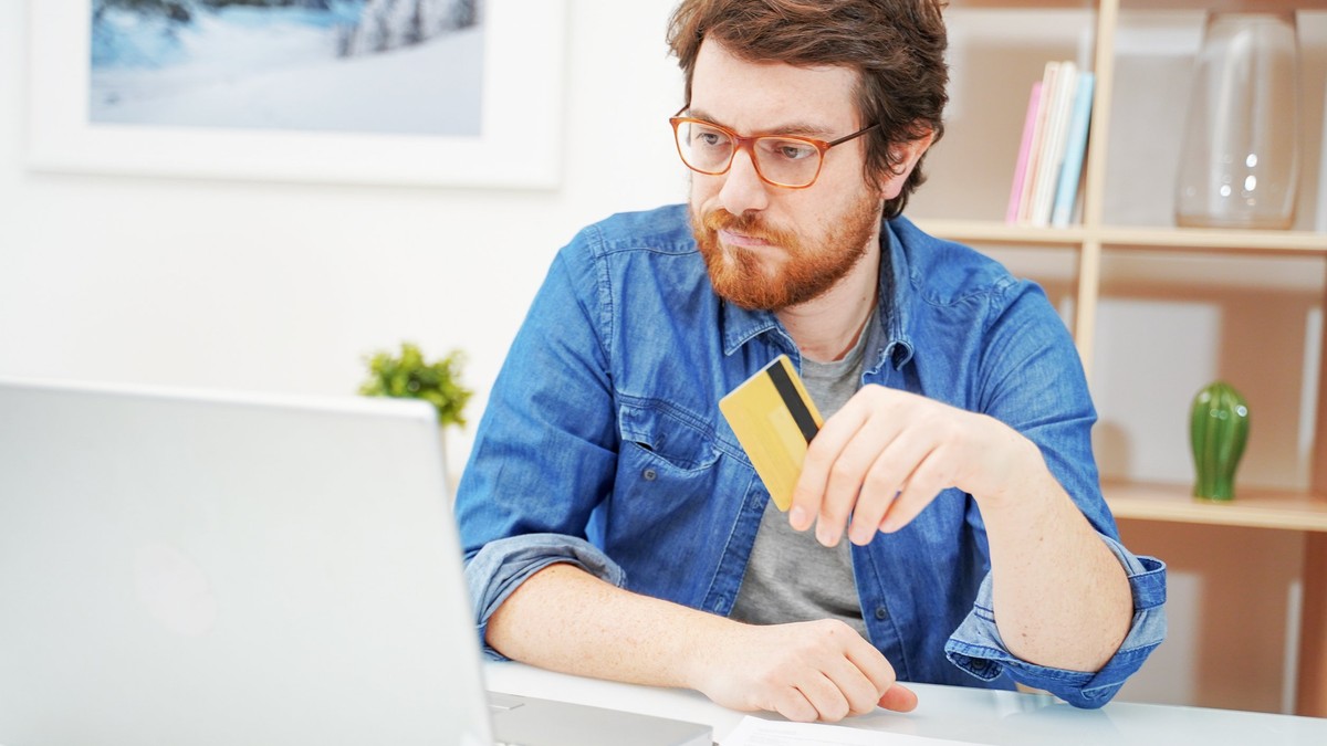 Ce este Ghiseul.ro - Imagine cu un bărbat care se află în faţa laptopului său, ţinând în mână un card bancar