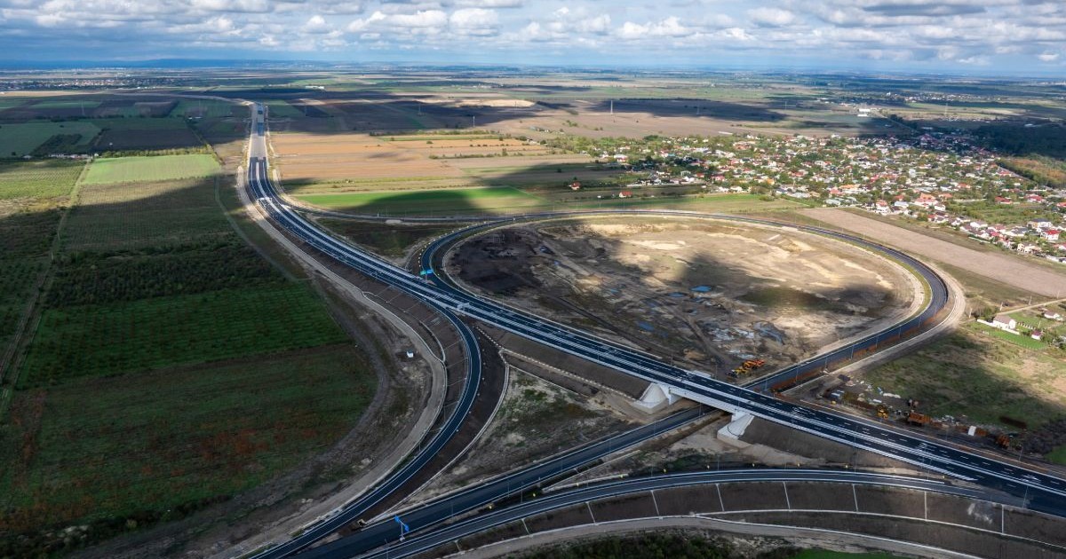 Fotografie aeriană cu acest drum de mare viteză, autostrada si noduri rutiere, campuri verzi si un cer cu nori