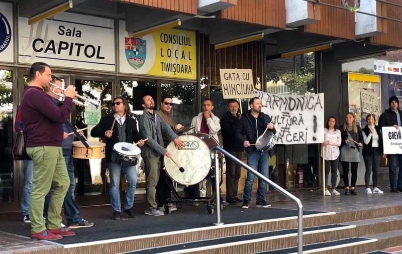 VIDEO&FOTO/ Protest cu tobe și trompete în fața Filarmonicii Banatul din Timișoara. Reclamă modul cum sunt tratați de către conducere