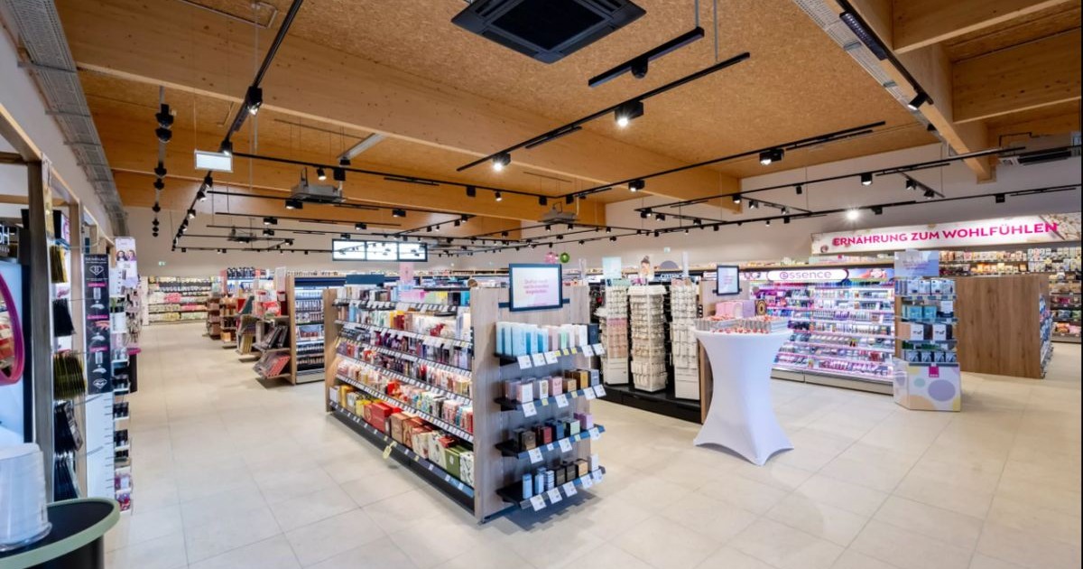 Mai multe standuri cu produse într-un magazin, pe jos se vede gresie, iar plafonul este din lemn maro