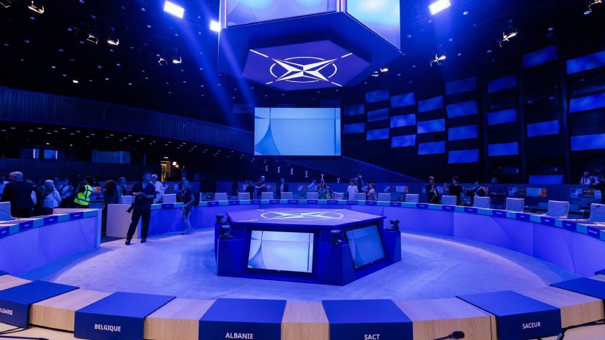 World Formu, locul din Haga unde s-a ținut Summitul NATO din iunie 2025, scaunele liderilor din țările aliate sunt goale, stema NATO este proiectată pe un ecran uriaș